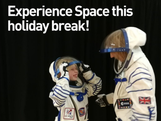 Child and parent dressed in space suits giggling and looking at each other